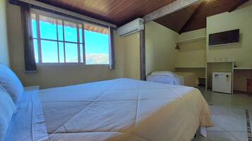 Une chambre d’hôtel avec un grand lit, une fenêtre avec des rideaux, un appareil de climatisation et une petite kitchenette.