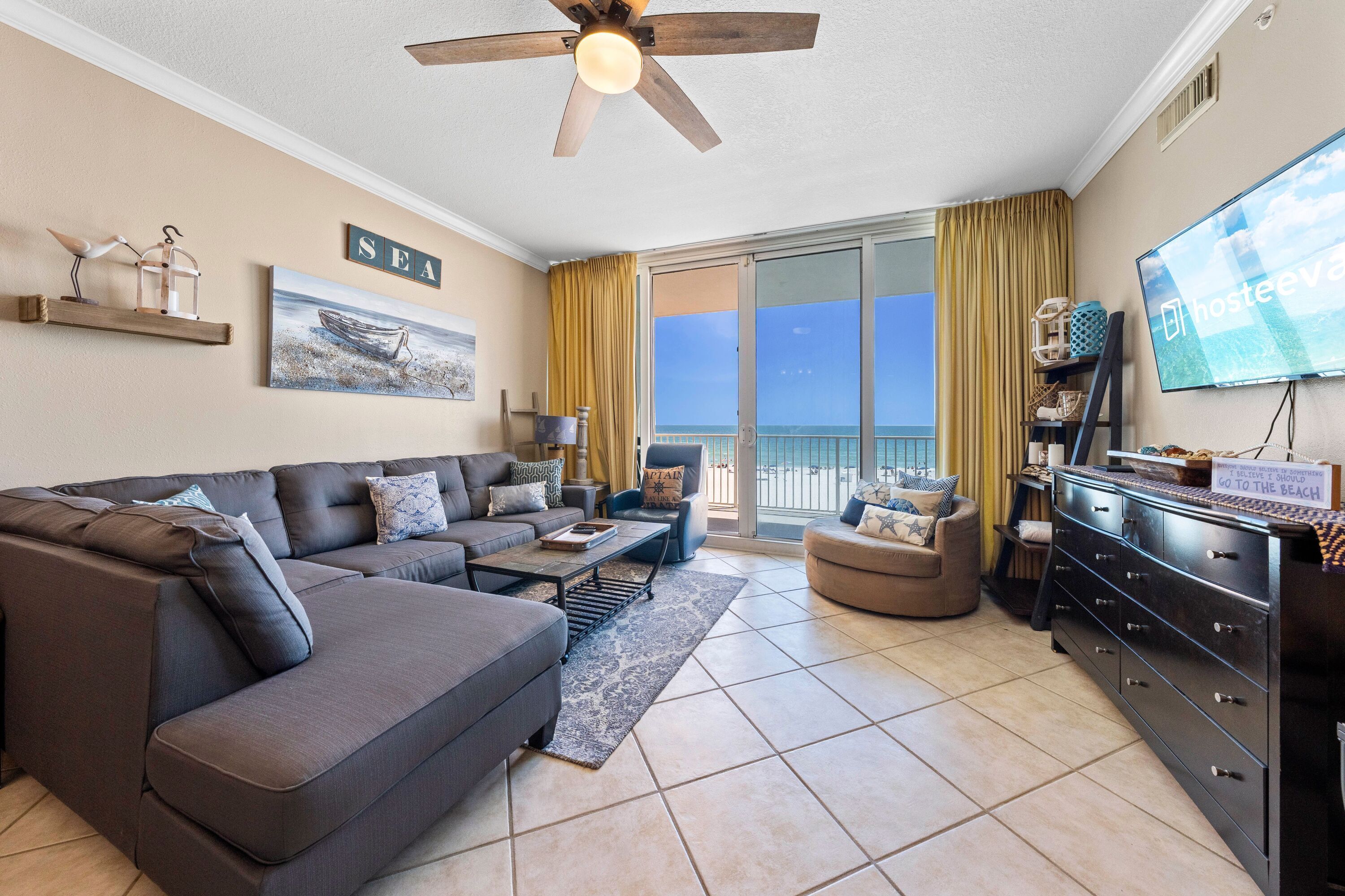 A living room with a sofa, armchair, TV, and a balcony with a view.