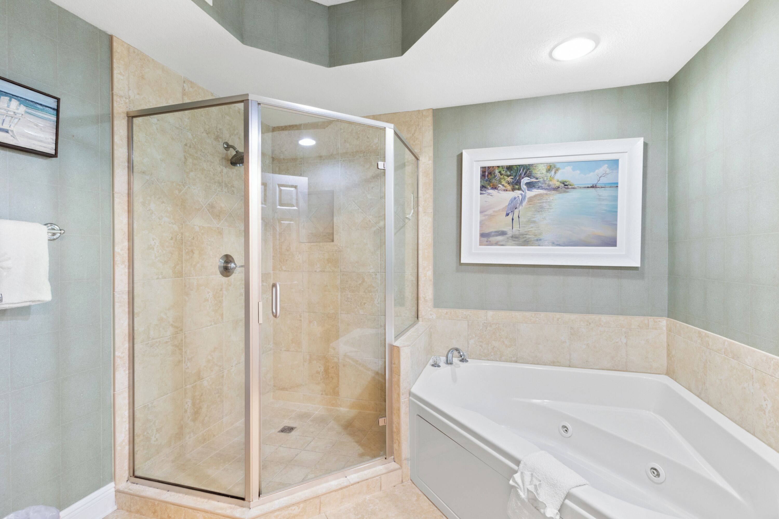 A modern bathroom with a glass-enclosed shower, a freestanding bathtub, and a framed landscape painting on the wall.