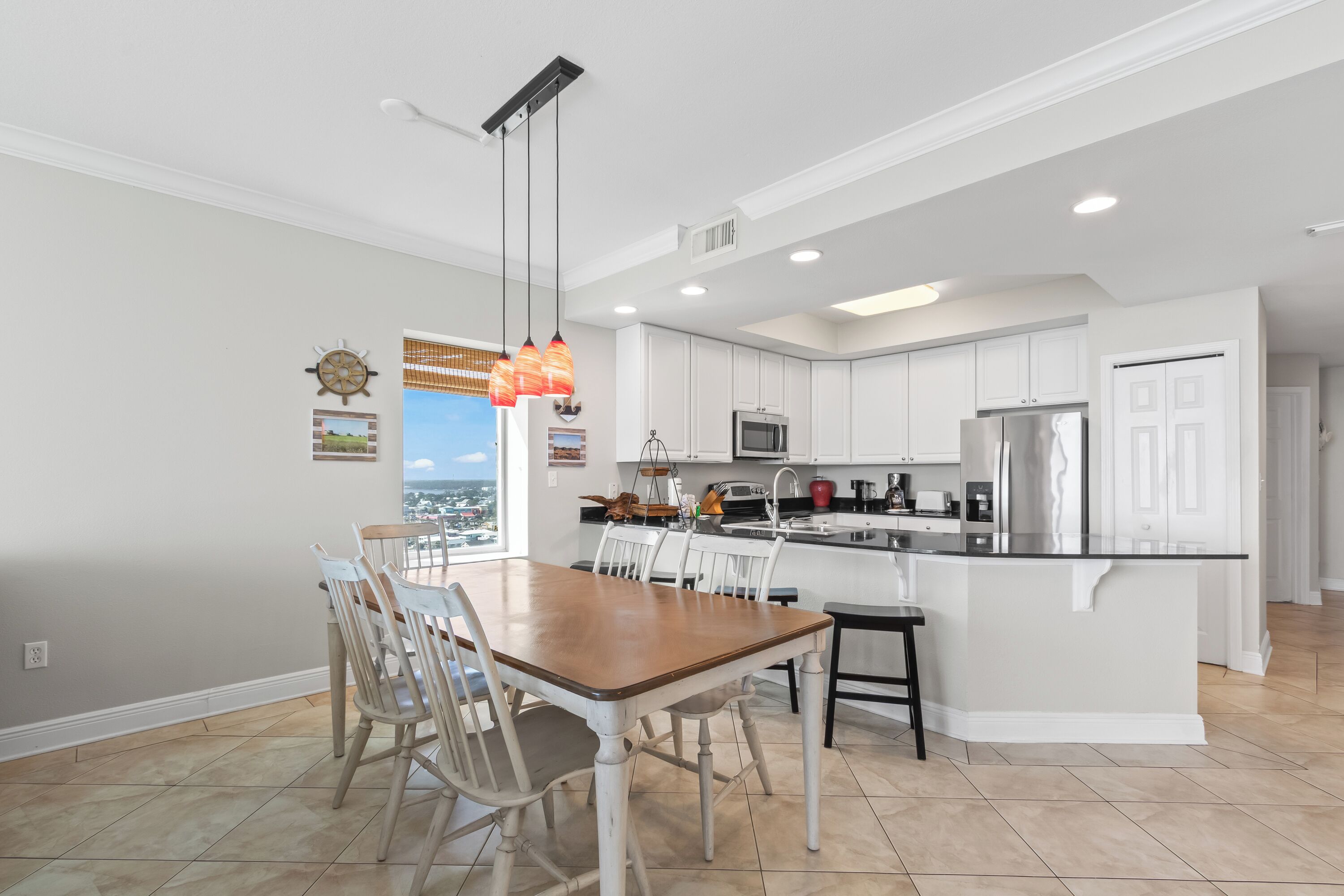 A modern kitchen with white cabinets, a central island, and a dining area with a wooden table and chairs.