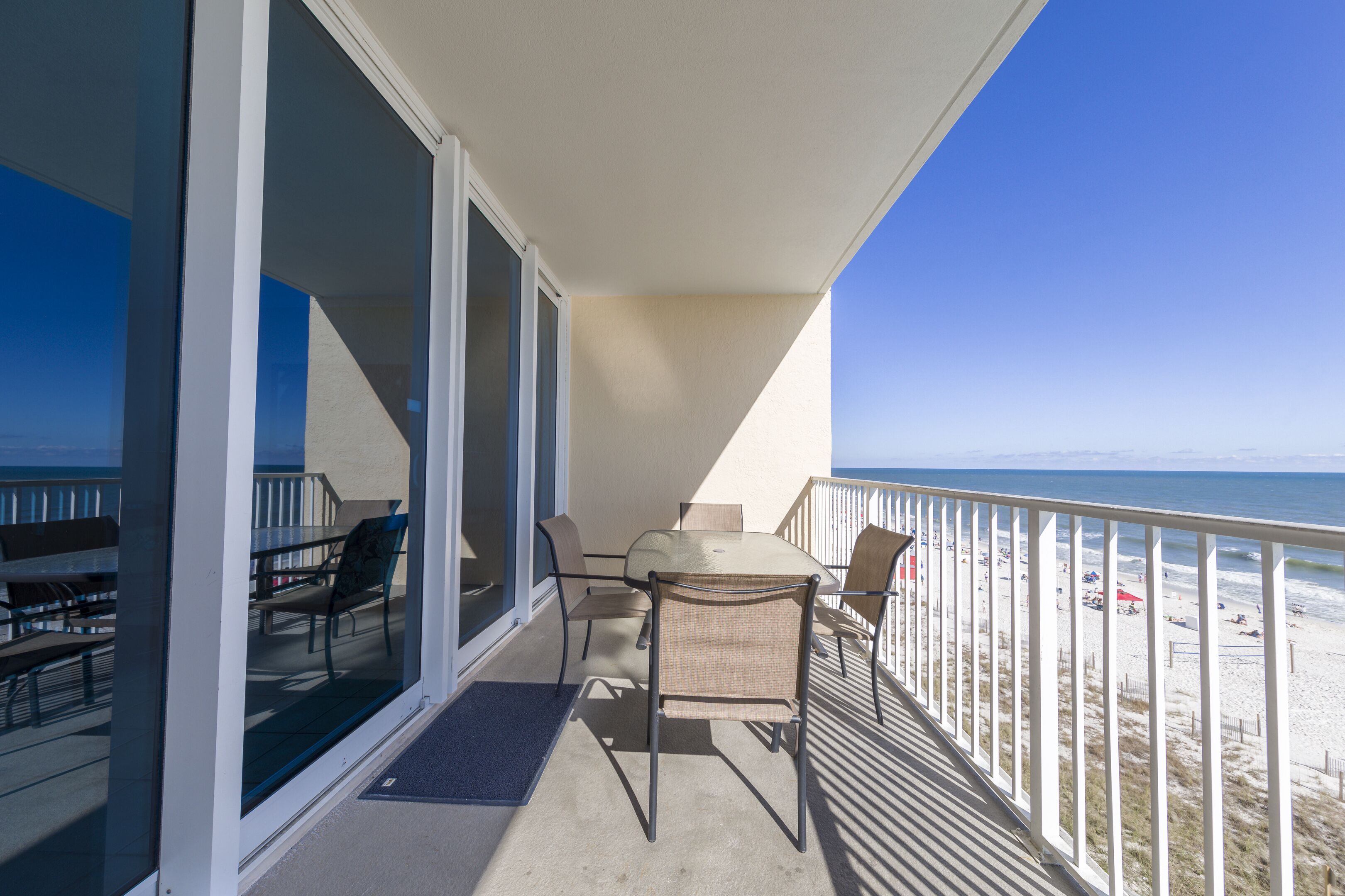 Un balcone con tavolo e sedie, vista sulla spiaggia.