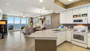 A spacious kitchen with a large island, white cabinetry, and a view to the outside. - San Carlos Condos (Gulf Shores)