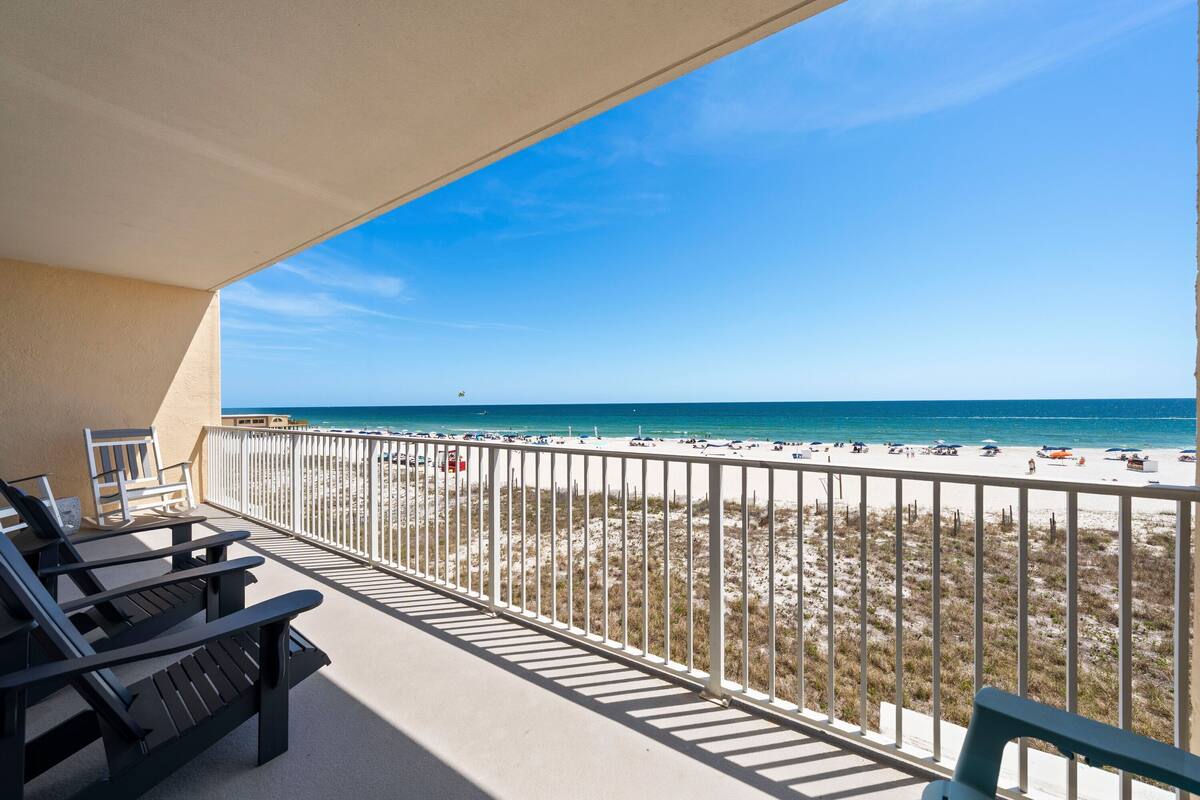 Un balcon donnant sur une plage, avec une balustrade et quelques chaises longues.