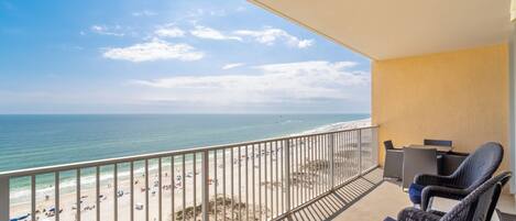 Ein Balkon mit Korbstühlen und Blick auf Strand und Meer.