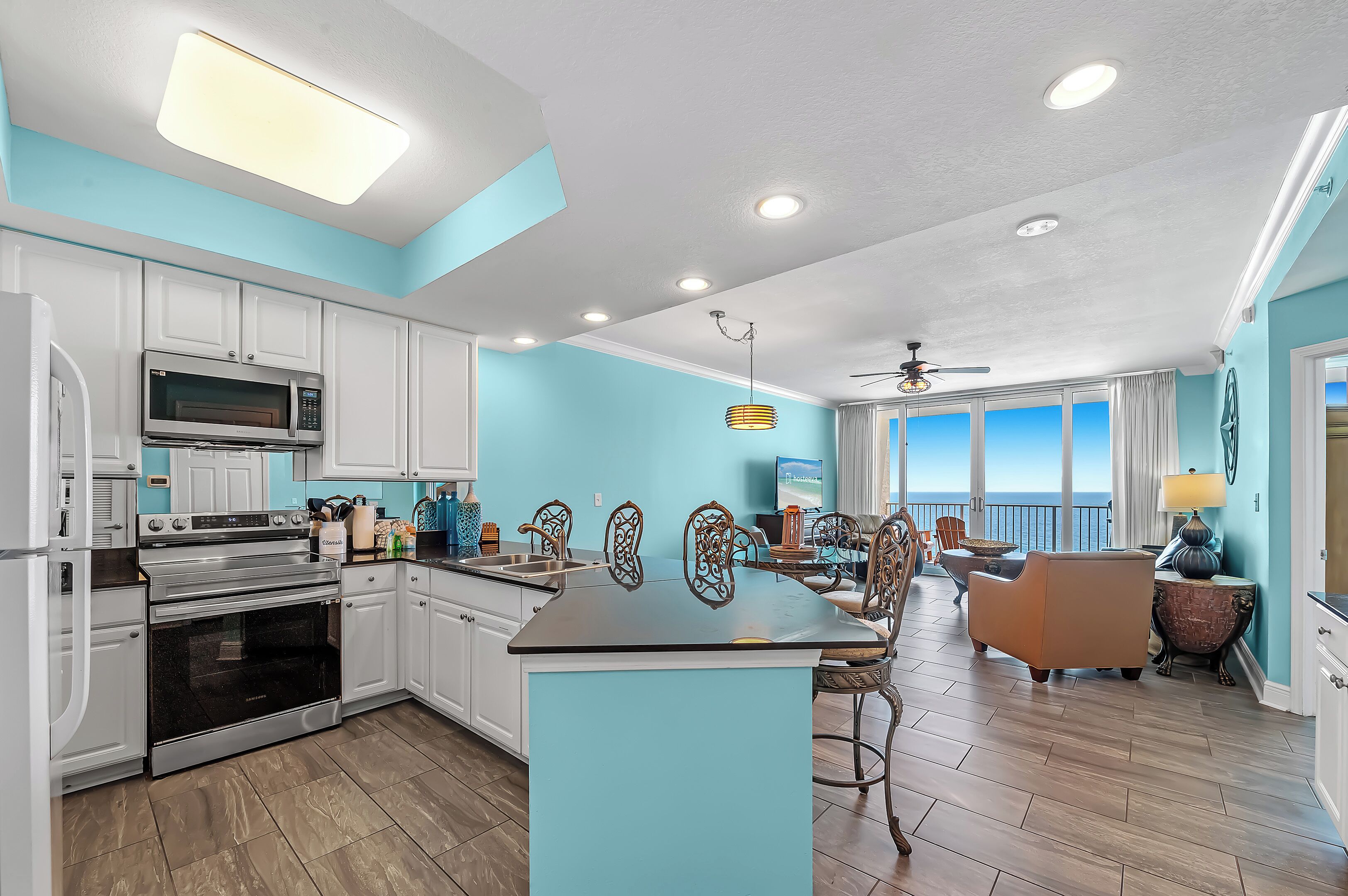 A modern kitchen with white cabinets, a central island, and a dining area with a view.