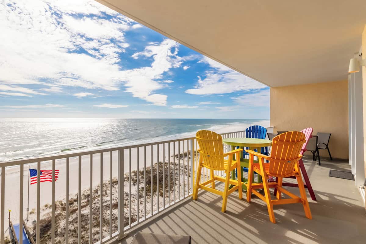 Un balcon avec vue sur l’océan, comprenant une table et des chaises, un drapeau et une balustrade.