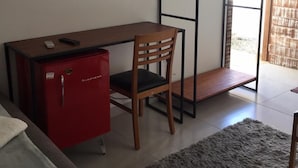Ein kleines Zimmer mit Schreibtisch, Stuhl und einem roten Schrank.