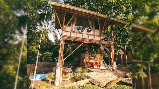 Eine rustikale Holzhütte mit Balkon, Whirlpool und einer Sitzgelegenheit, inklusive Fahrrad.