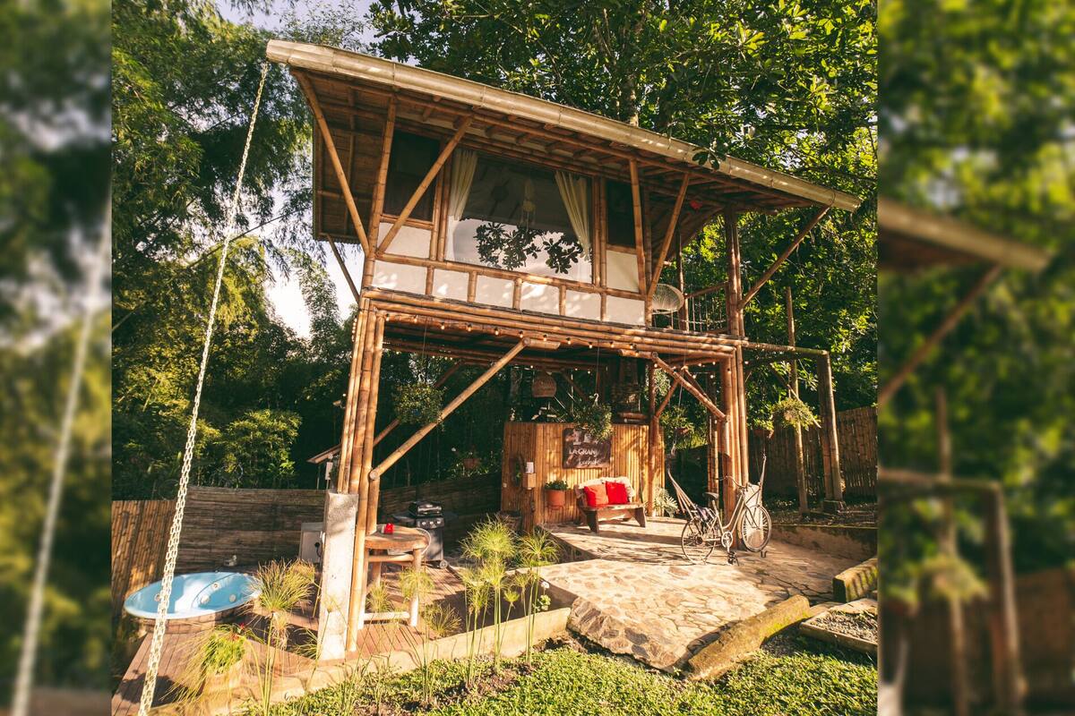 Una estructura rústica de madera con balcón, jacuzzi y una zona de estar con una bicicleta.