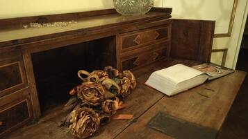 A wooden desk with a glass bowl, a book, and dried flowers.