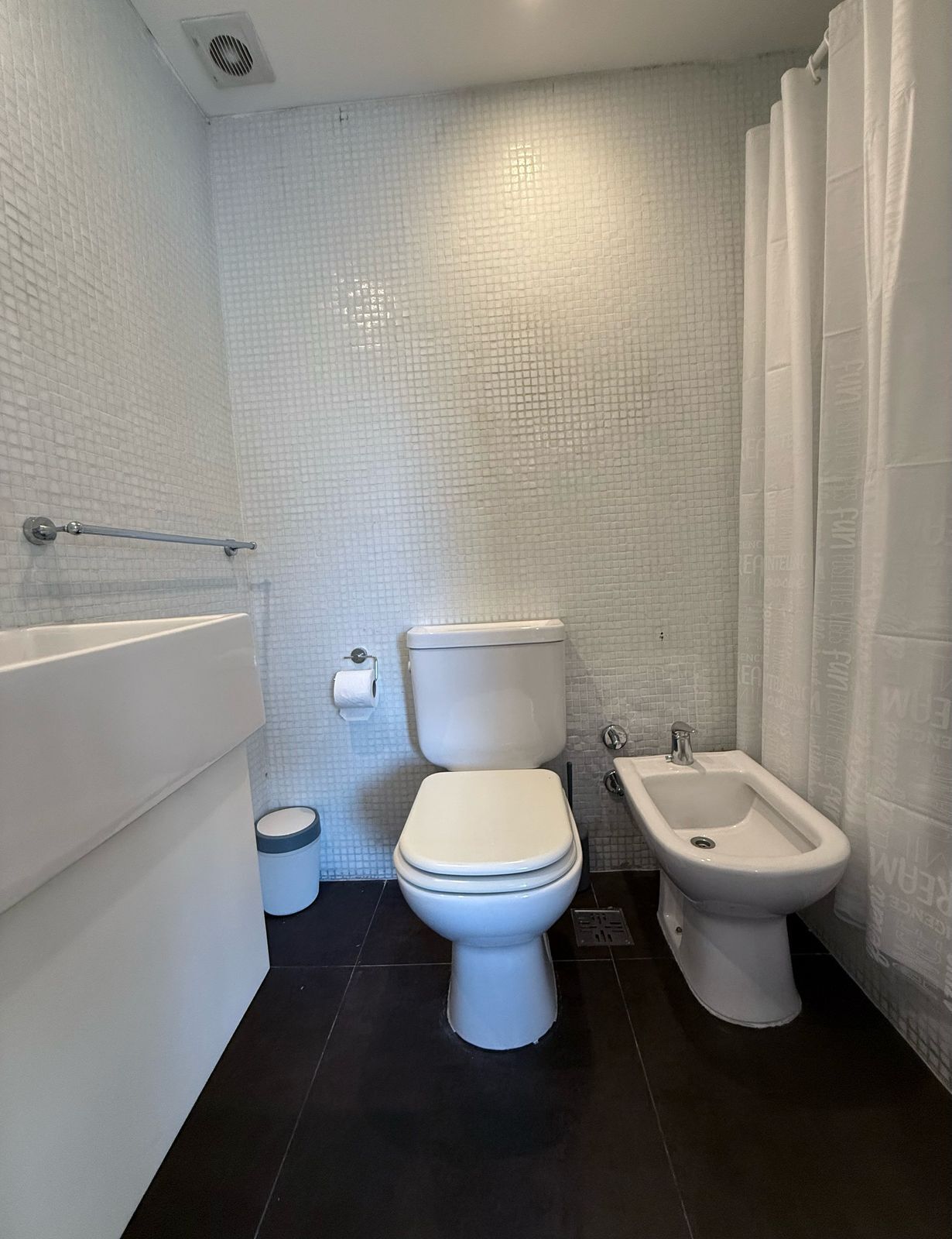Une salle de bain équipée de toilettes, d’un bidet et d’un porte-serviettes.