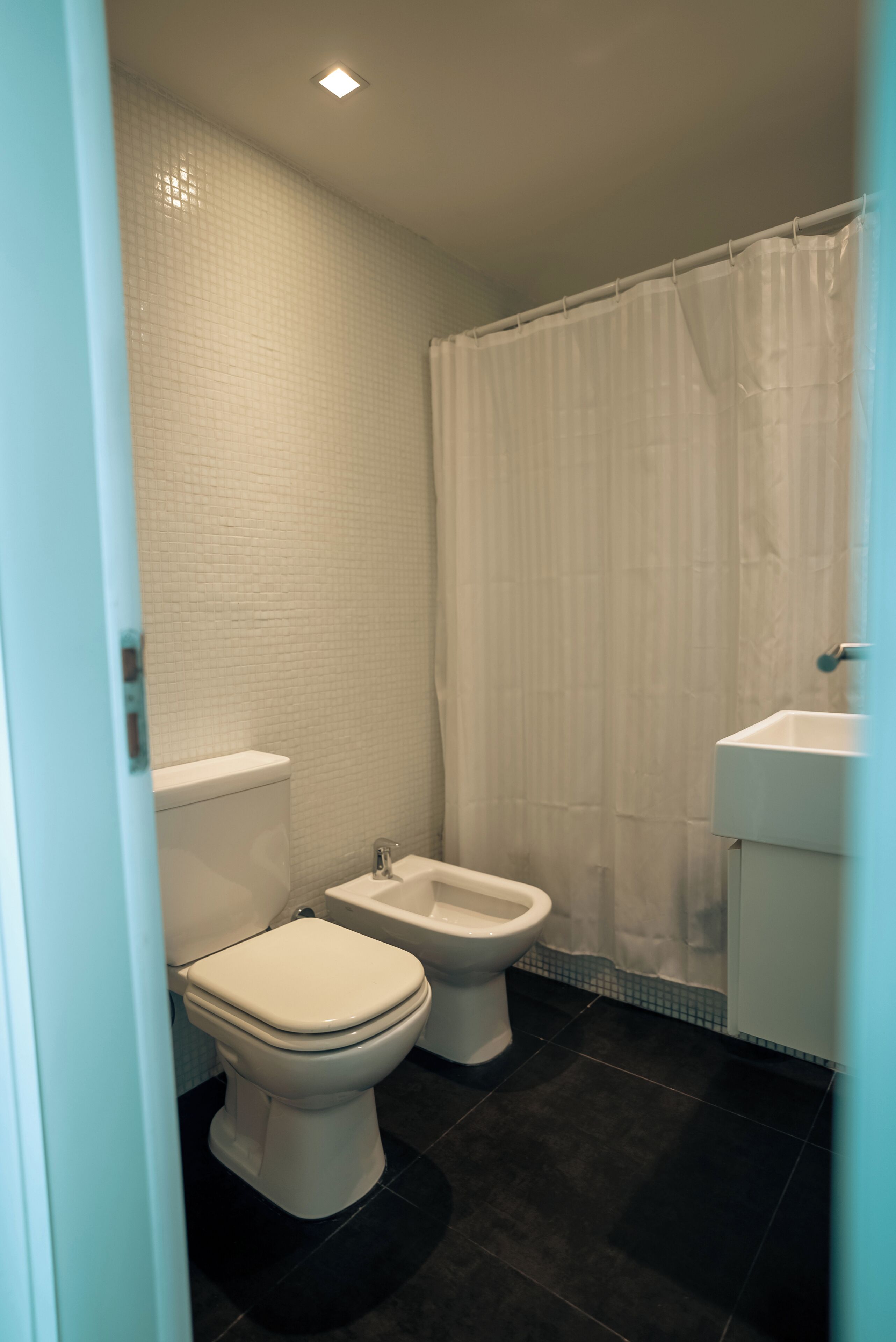 Un baño con inodoro, bidé y lavamanos.
