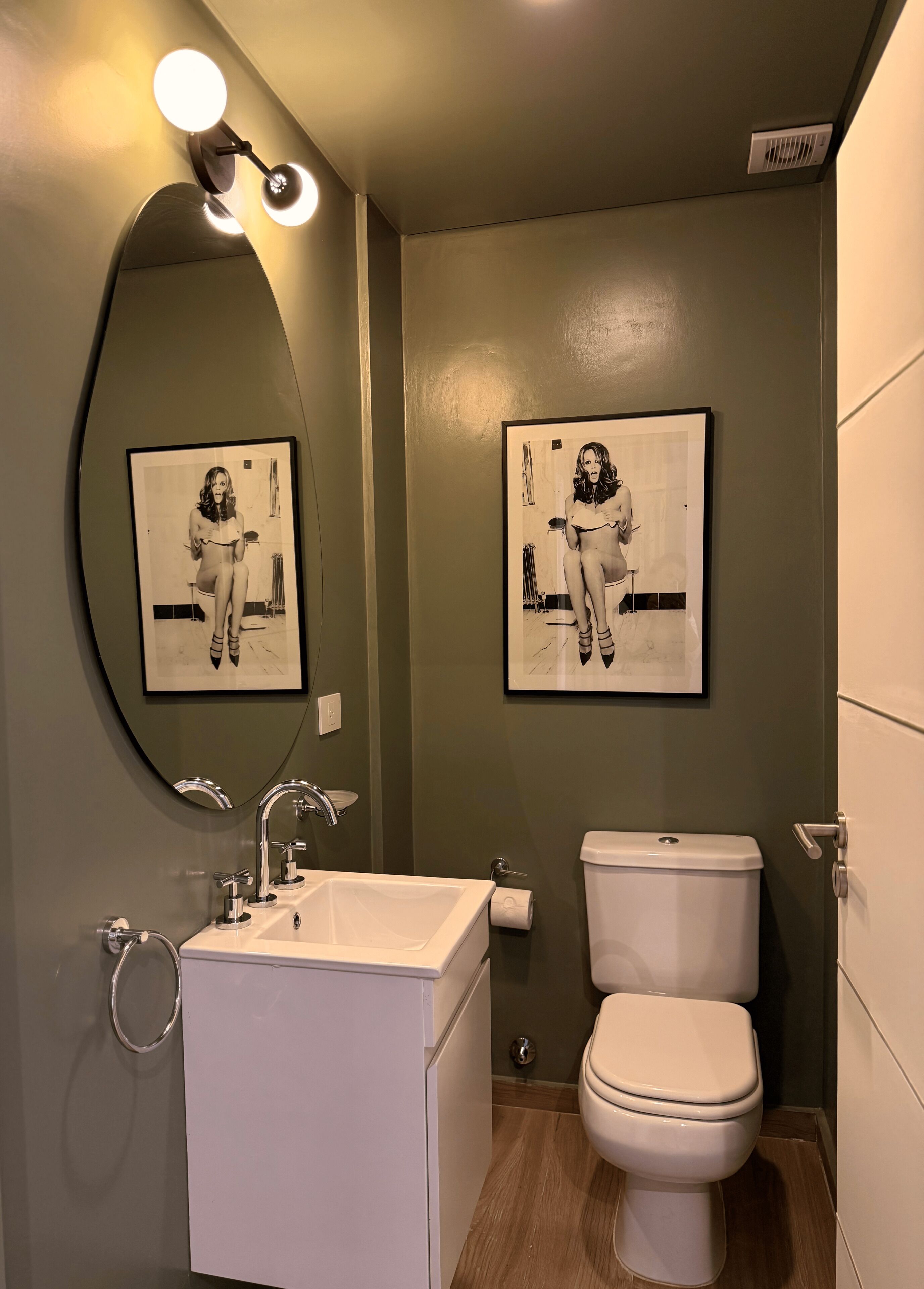 Ein Badezimmer mit einem weißen Waschbecken, einer Toilette und zwei gerahmten Bildern an der Wand.