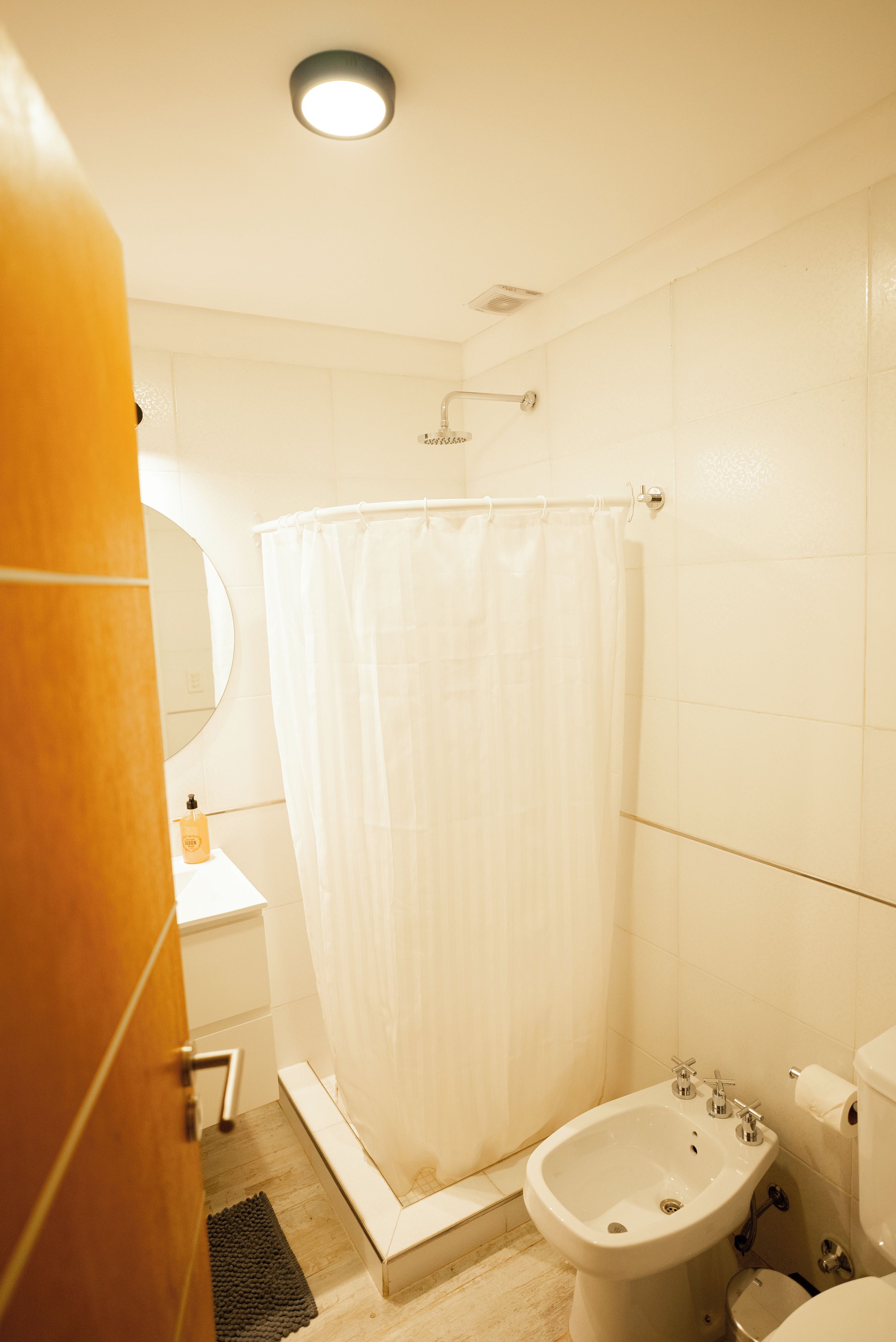 A bathroom with a shower curtain, a sink, a mirror, and a toilet.