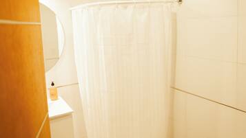 A bathroom with a shower curtain, a sink, a mirror, and a toilet.