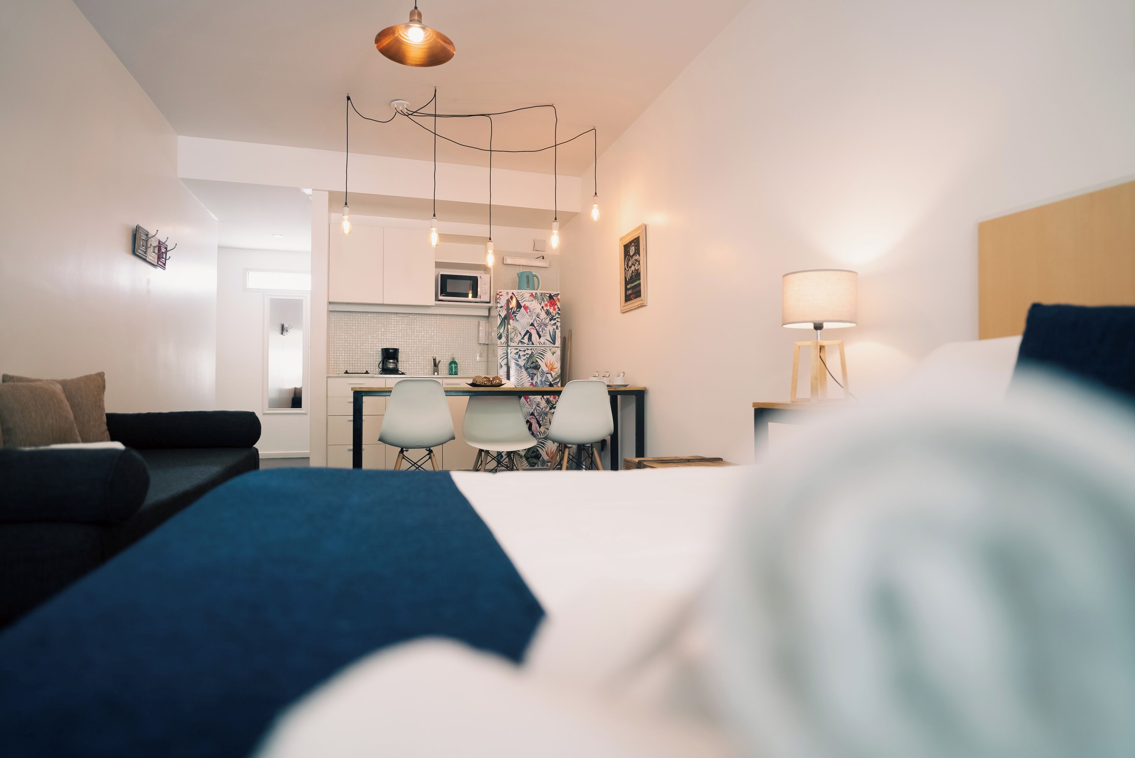 Una habitación de hotel moderna con cama, sofá, escritorio y kitchenette.