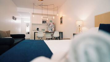 Una habitación de hotel moderna con cama, sofá, escritorio y kitchenette.