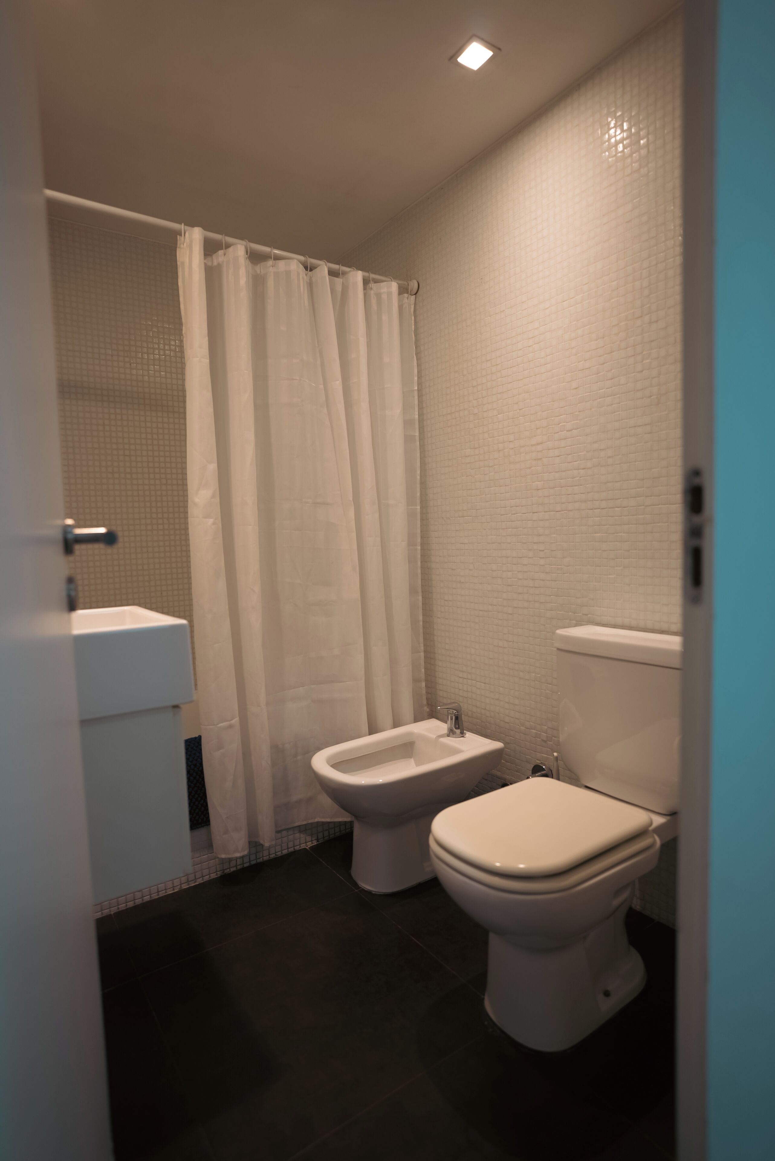 Et badeværelse med toilet, bidet og håndvask.