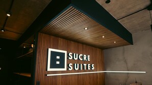 A sign for 'SUCRE SUITES' with a modern design, wooden paneling, and a simple, clean font. - Sucre Suites (Buenos Aires)