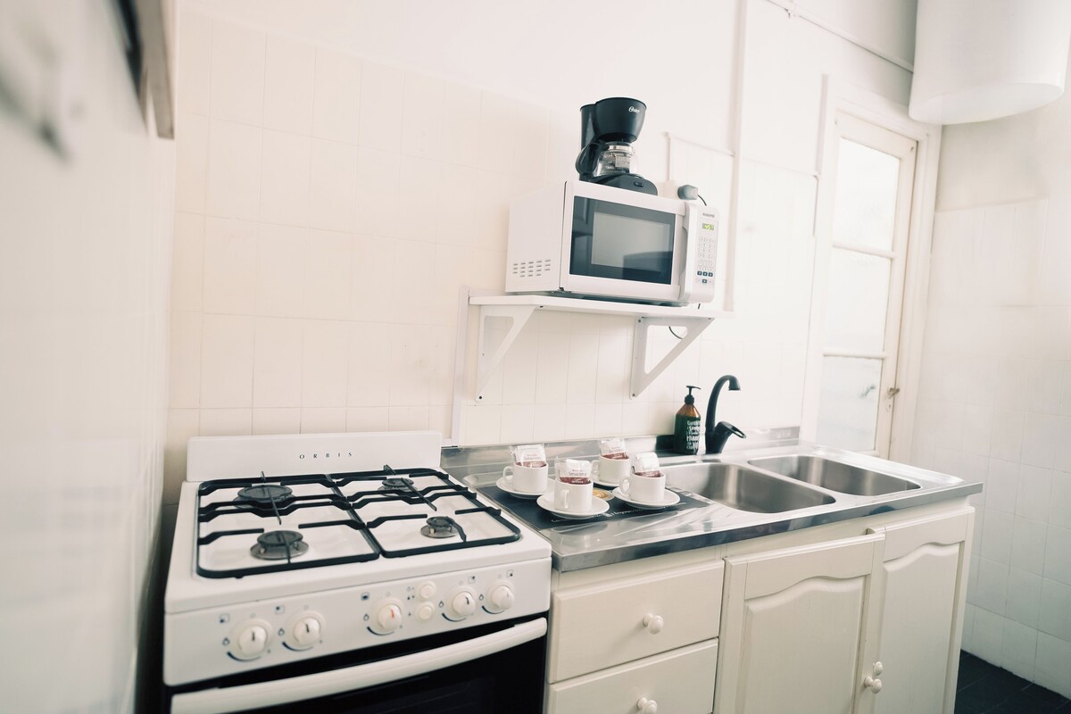 A kitchen with a gas stove, a microwave, a sink, and a coffee maker.