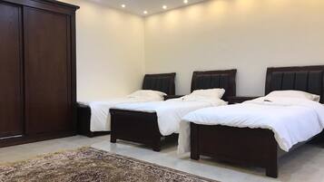 A bedroom with two single beds, a large wardrobe, and a patterned rug.