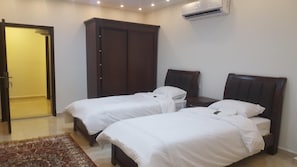Una habitación de hotel con dos camas individuales, un armario y un equipo de aire acondicionado.