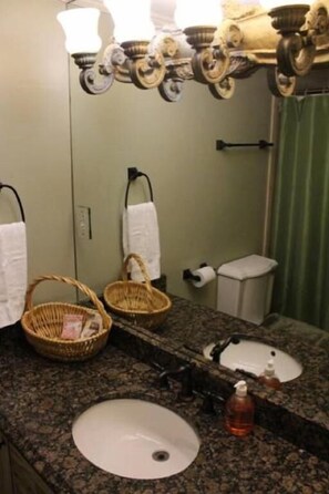 A bathroom with a granite countertop, two sinks, a mirror, a towel rack, and a basket. - The MIdtown Atlanta Escape (Atlanta)