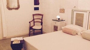 A bedroom with a bed, a chair, a nightstand, and a mirror. - Bnb Dragonetti (Manduria)