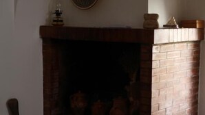 A room with a brick fireplace, a wooden bucket, and two decorative plates on the wall. - Bnb Dragonetti (Manduria)