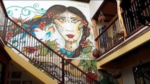 A staircase with a mural on the wall, featuring a woman's face surrounded by floral and abstract designs. - Hotel La Cosecha (Pereira)