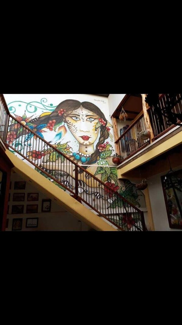 A staircase with a mural on the wall, featuring a woman's face surrounded by floral and abstract designs.