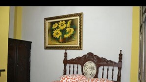 A bedroom with a wooden bed, a floral pillow, and a framed painting of sunflowers on the wall. - Hotel La Cosecha (Pereira)