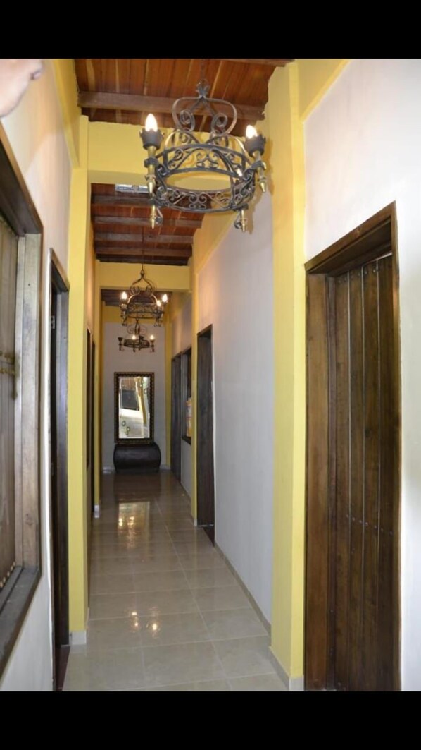 A hallway with wooden doors, a tiled floor, and a chandelier. - Hotel La Cosecha (Pereira)
