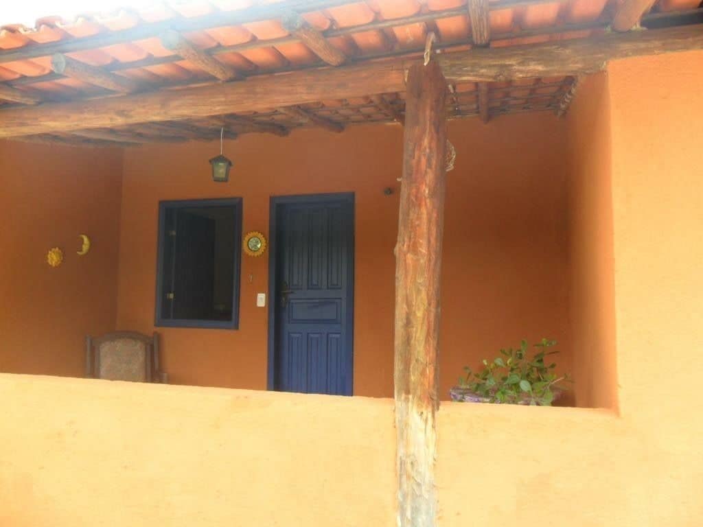 Um edifício com porta azul, janela, um poste de madeira e um candeeiro suspenso.