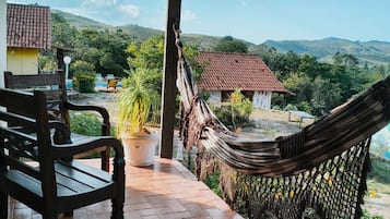 A covered outdoor area with a hammock, a bench, and a potted plant.