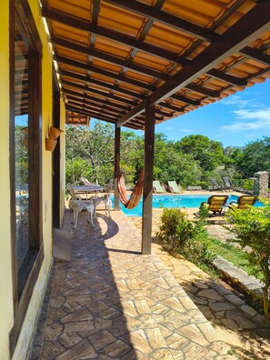 A covered outdoor area with a pool, stone flooring, and outdoor furniture. - Pousada Chalés Barriga Da Lua (Santana do Riacho)