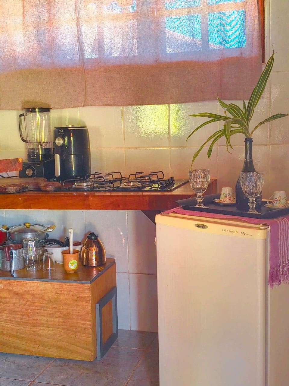 A compact kitchen with a refrigerator, a stove, a blender, and a coffee maker.