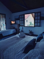 Quarto com cama, televisão, janela e ventilador.