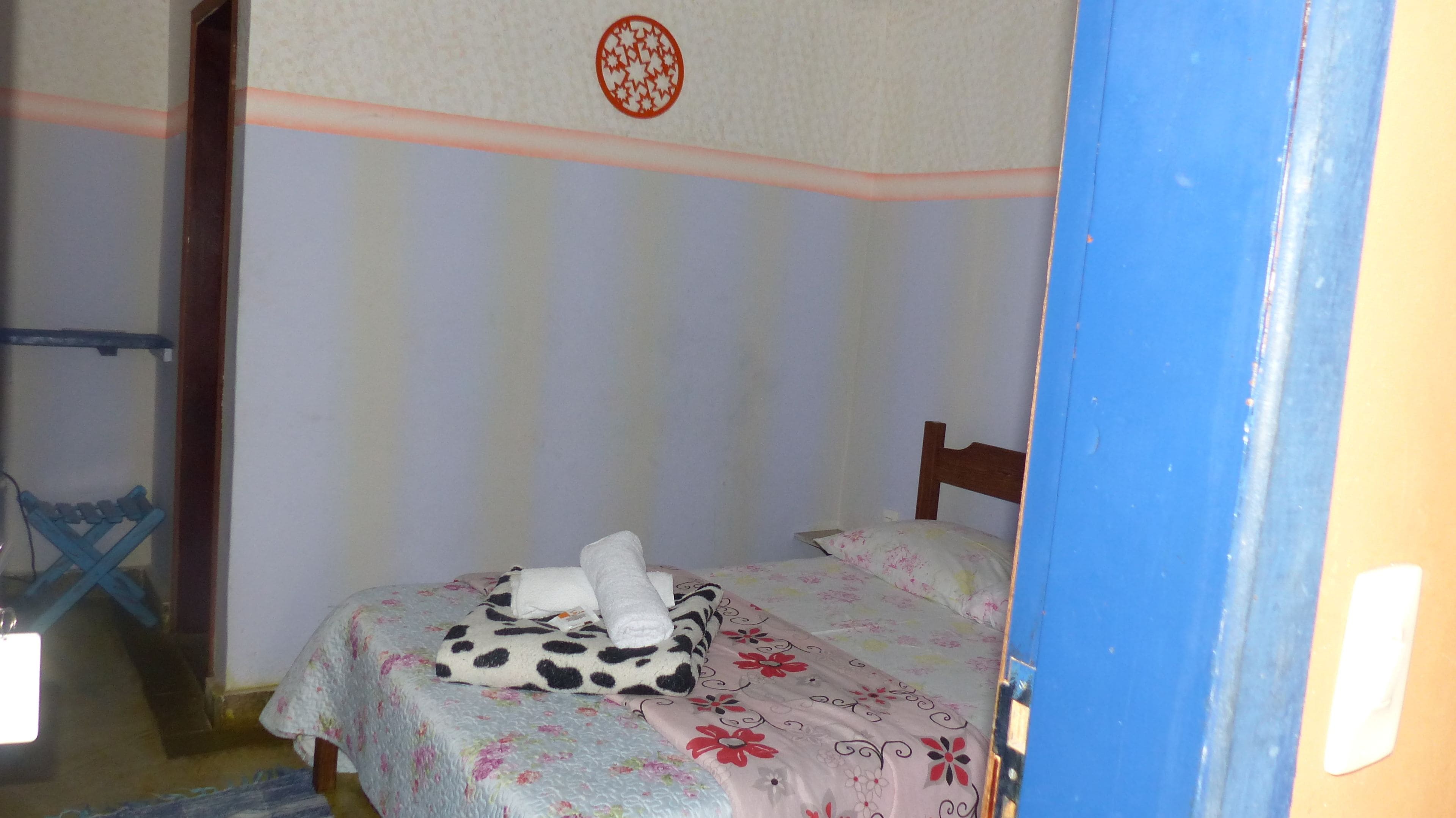 Un dormitorio con cama, cabecera de madera, colcha estampada con flores y decoración en la pared.