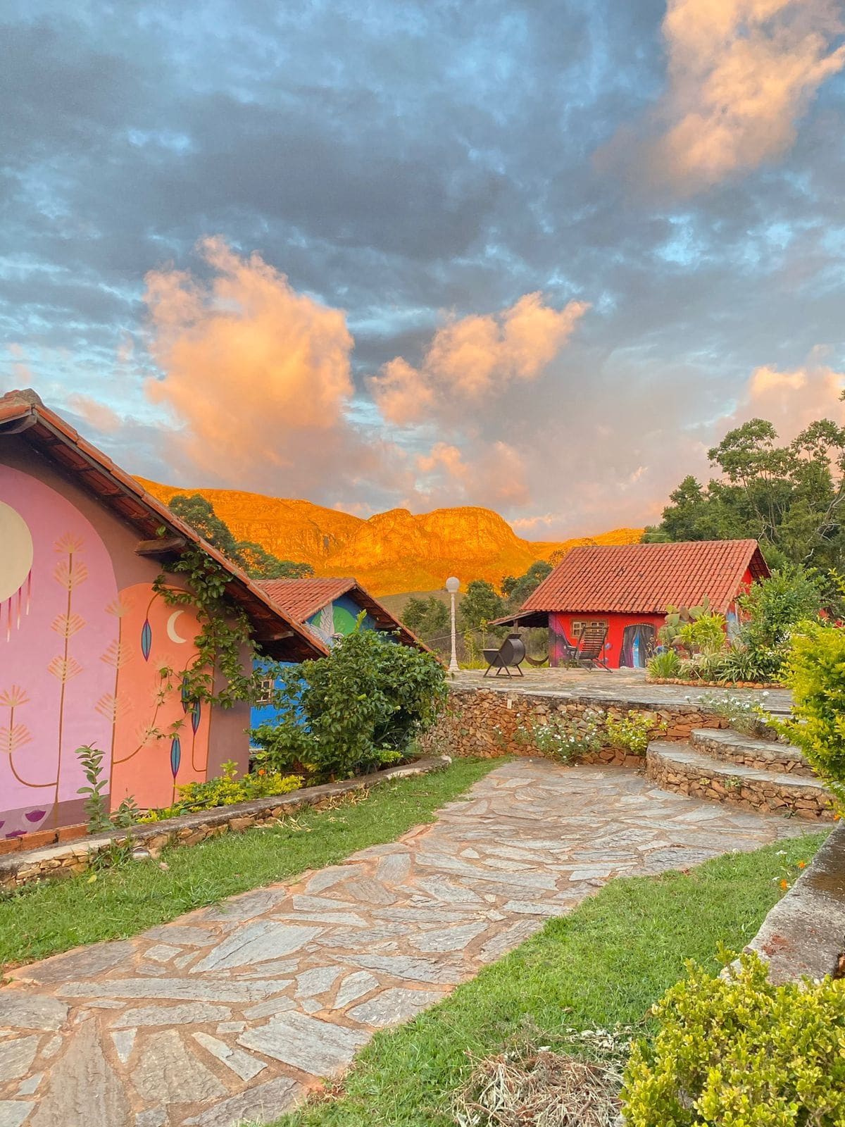 A courtyard with stone pathways, colorful buildings, and a mountainous backdrop.
