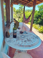 Un espacio de estar techado al aire libre con una mesa, una botella de vino y una copa de vino.