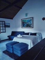 Un dormitorio con cama, sofá, un cuadro y ventana.