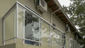 A building with large windows, a balcony, and an air conditioning unit. - Pousada Colibri (Paraty)