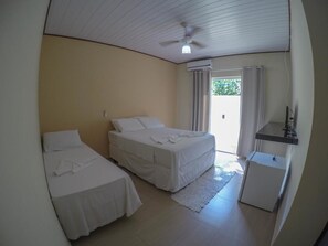 A room with two beds, a ceiling fan, an air conditioning unit, a small desk, and a view of the outside. - Pousada Colibri (Paraty)