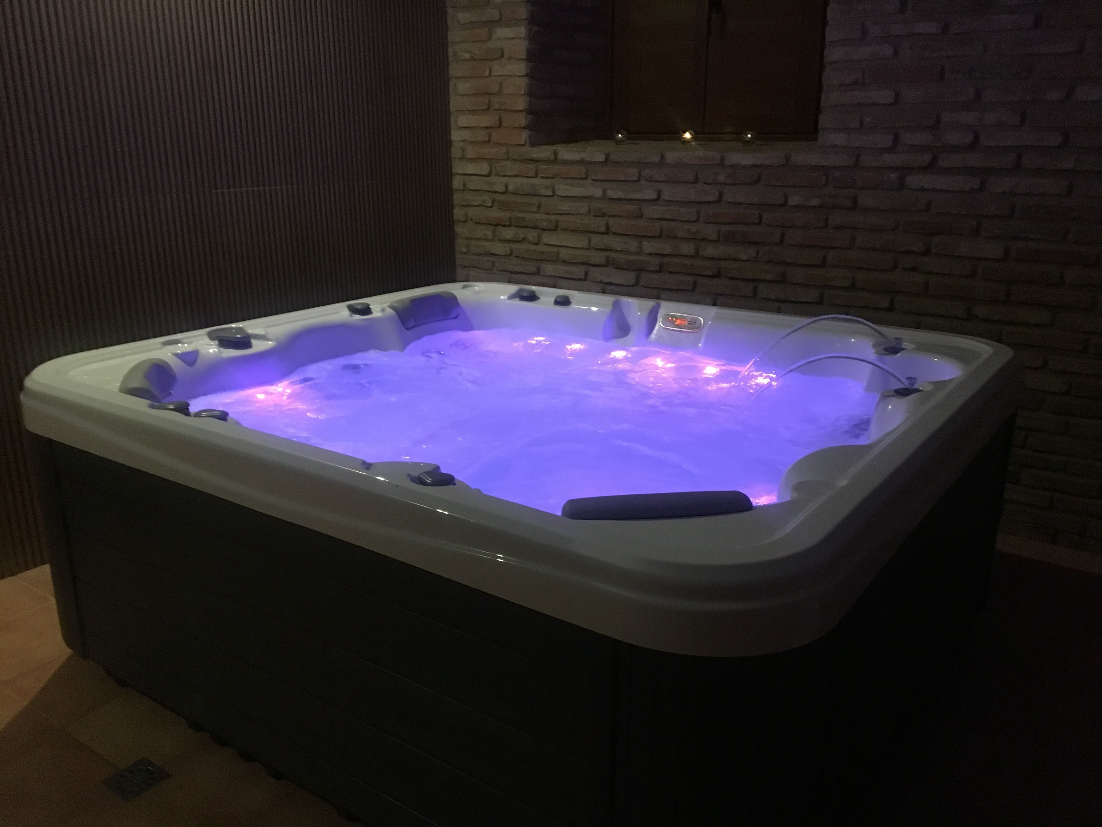 Un jacuzzi con panel de control digital, frente a un muro de ladrillo.