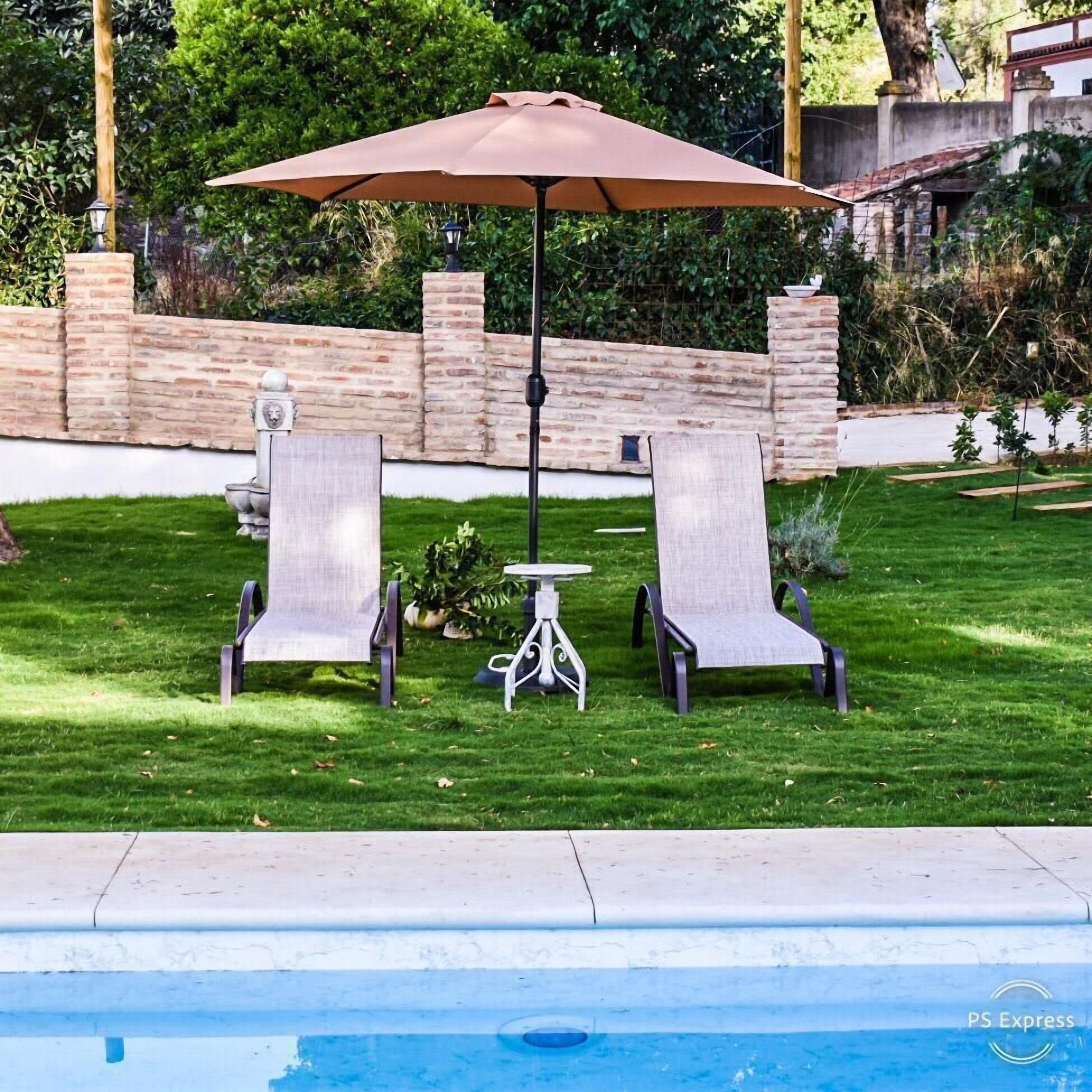 Een zwembadterras met twee ligbedden, een tafel en een parasol.