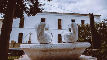 Una fuente de piedra con dos esculturas de cisnes frente a un edificio blanco con múltiples ventanas.