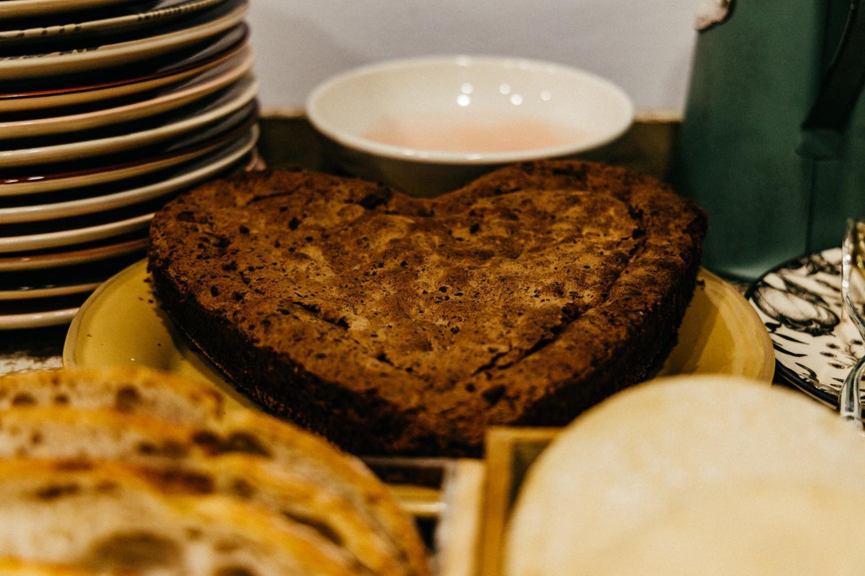Una pila de platos, un pastel con forma de corazón y un tazón de sopa.