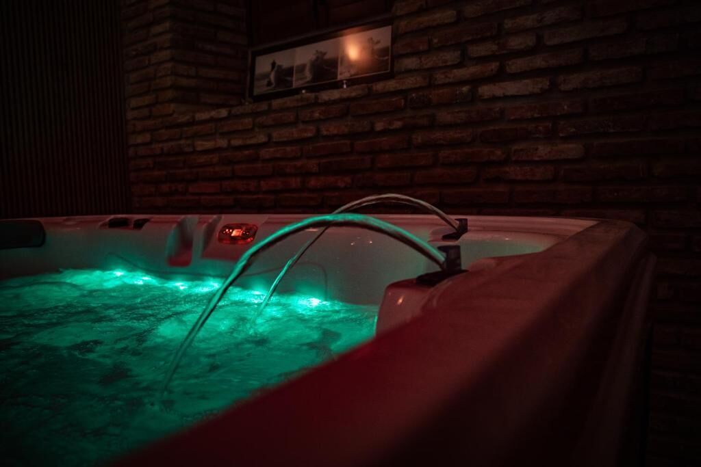 A hot tub with green lighting against a brick wall.