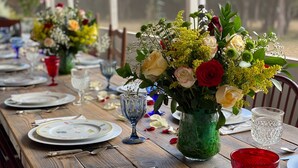 A dining table set with plates, cutlery, and glassware, with floral centerpieces in green vases. - BellaVida B&B and Retreat (Wimberley)